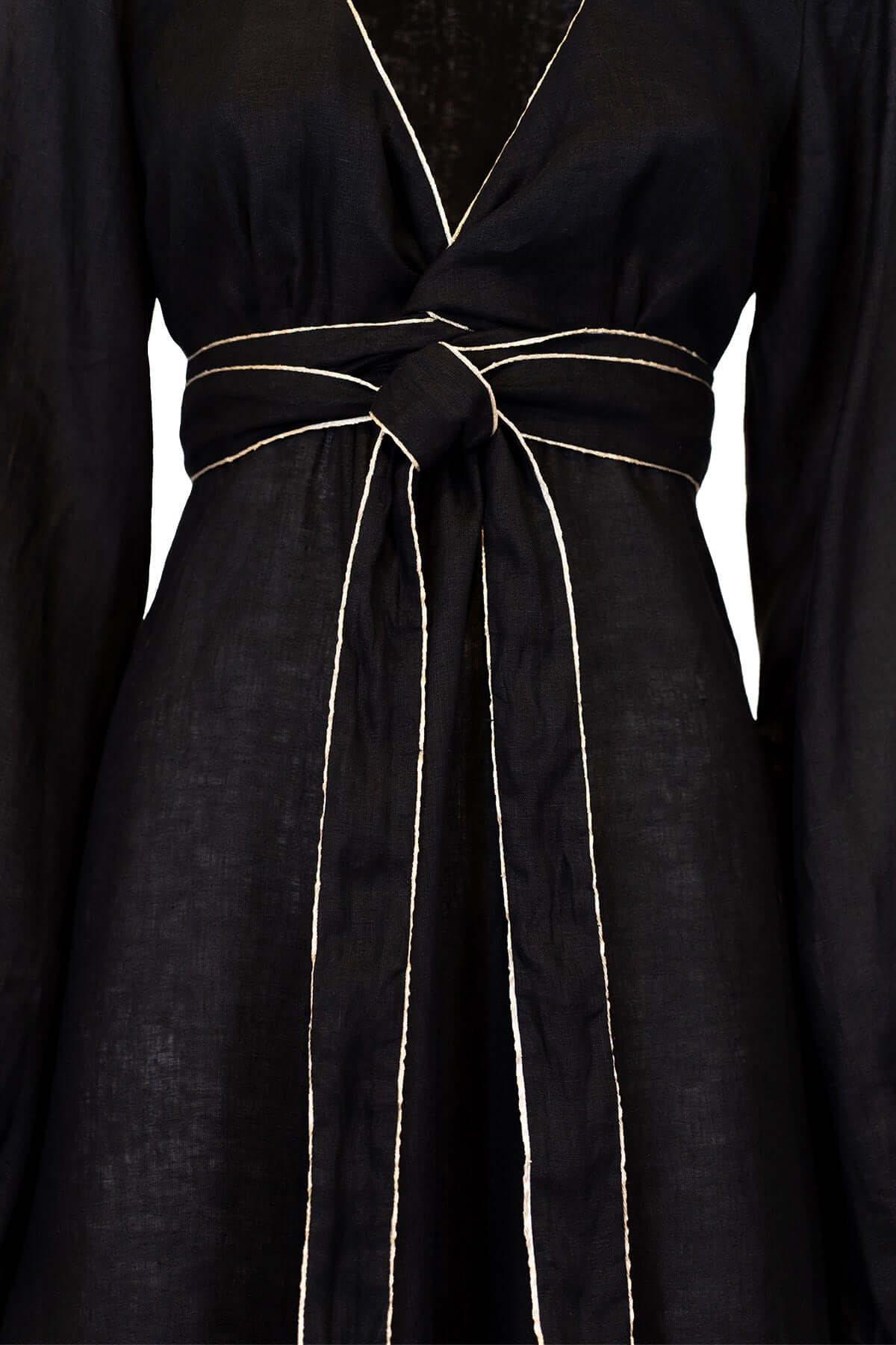 Close-up of a long linen dress with a V-neck and puff sleeves, featuring a tied waist and gold piping.