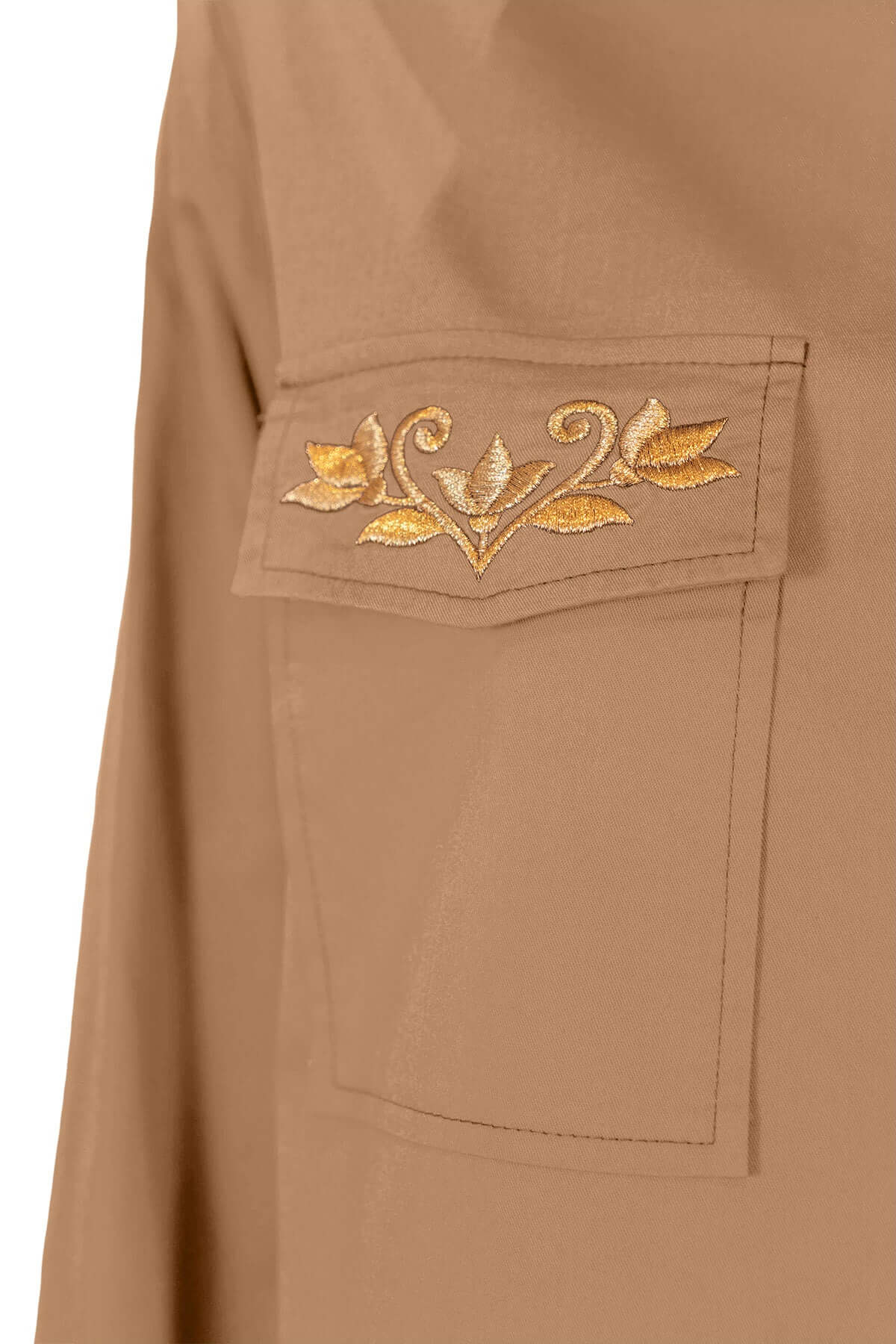 Close-up of pocket detail featuring elegant golden embroidery on a tan shirt.