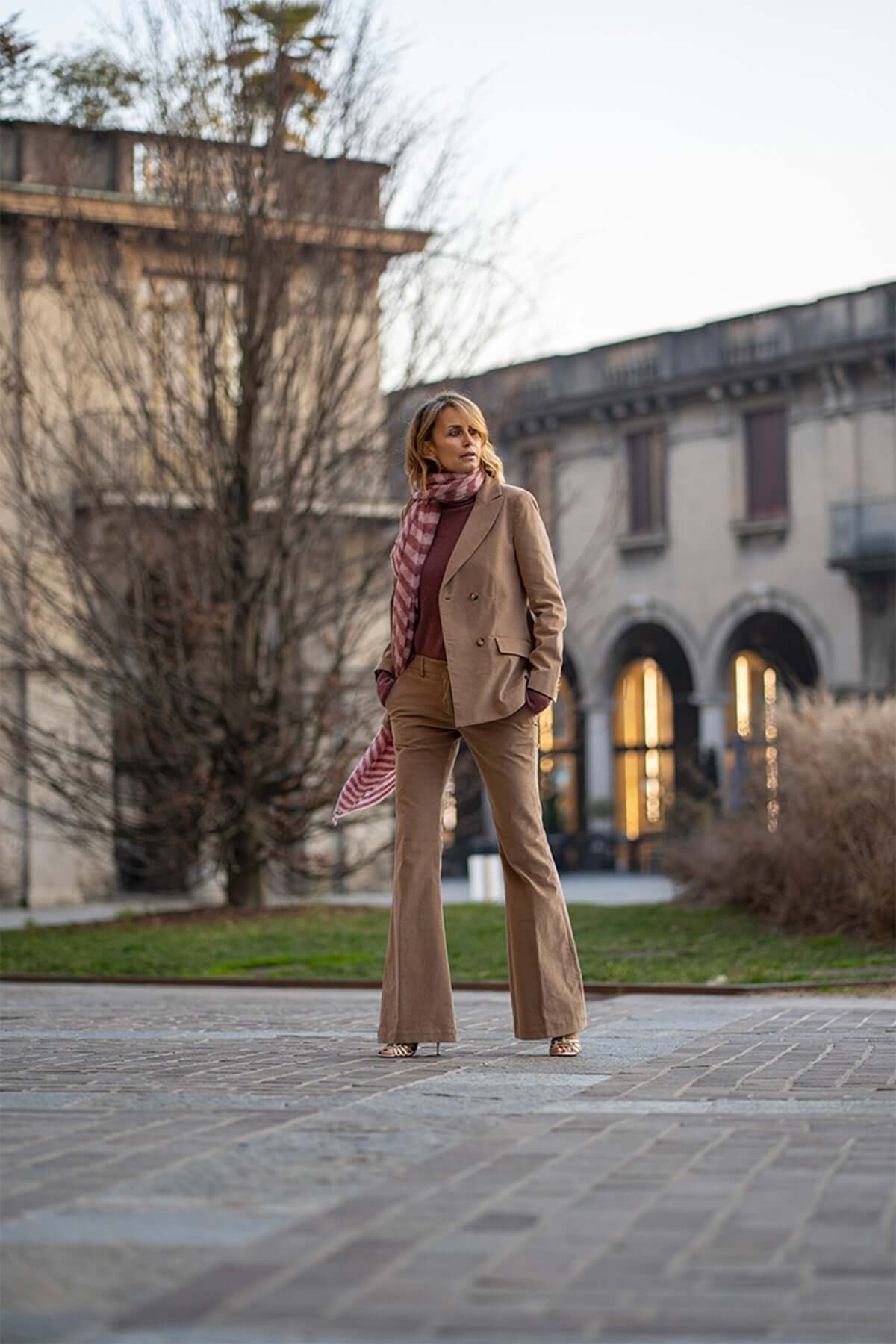 Model in a double-breasted velvet blazer and stylish pants, showcasing elegance in an outdoor urban setting.
